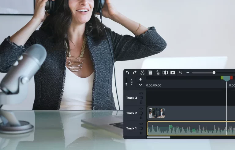 A woman edits audio volume in headphones using Camtasia's timeline.