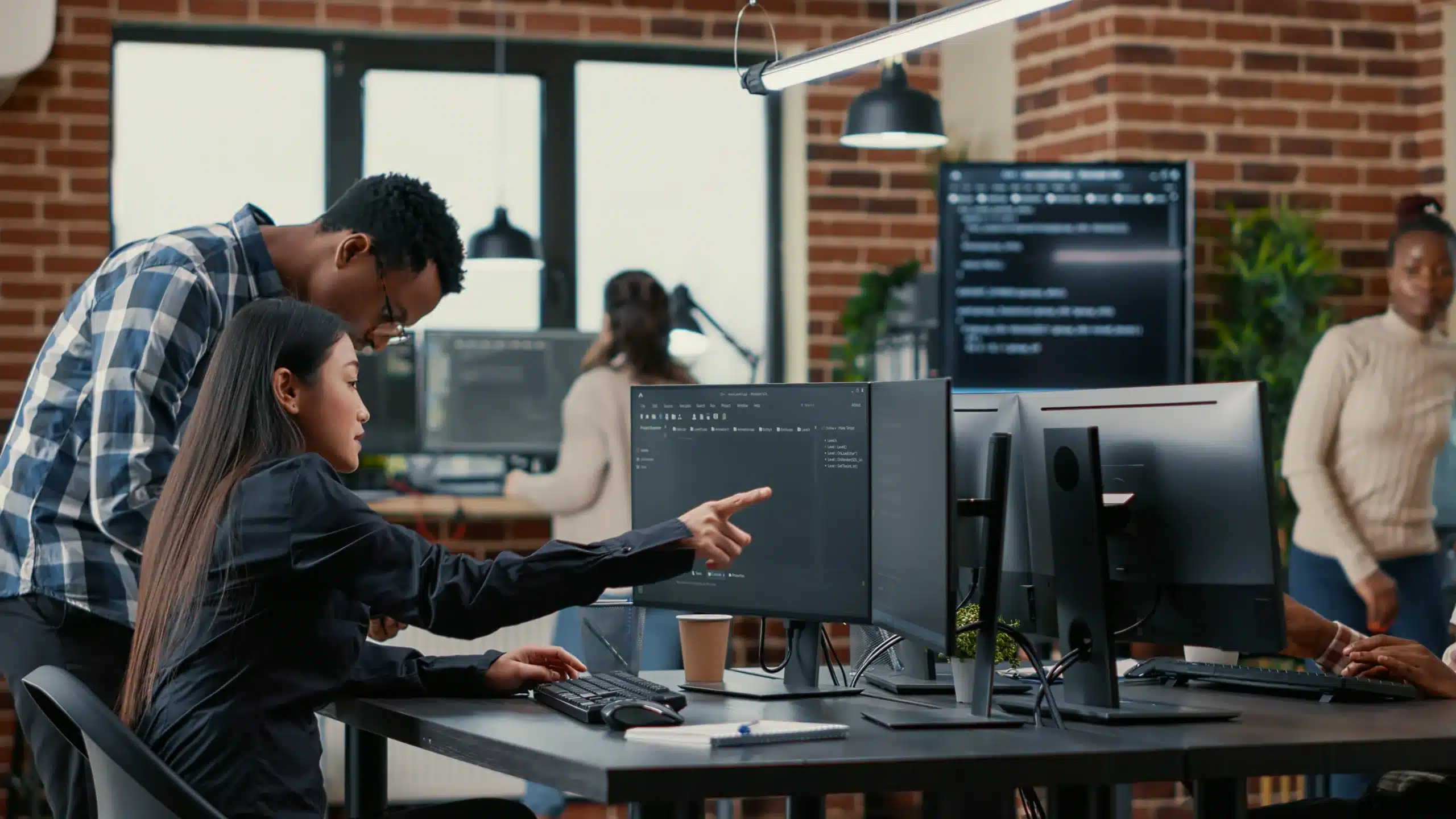 Two IT professionals pointing at a screen displaying code.